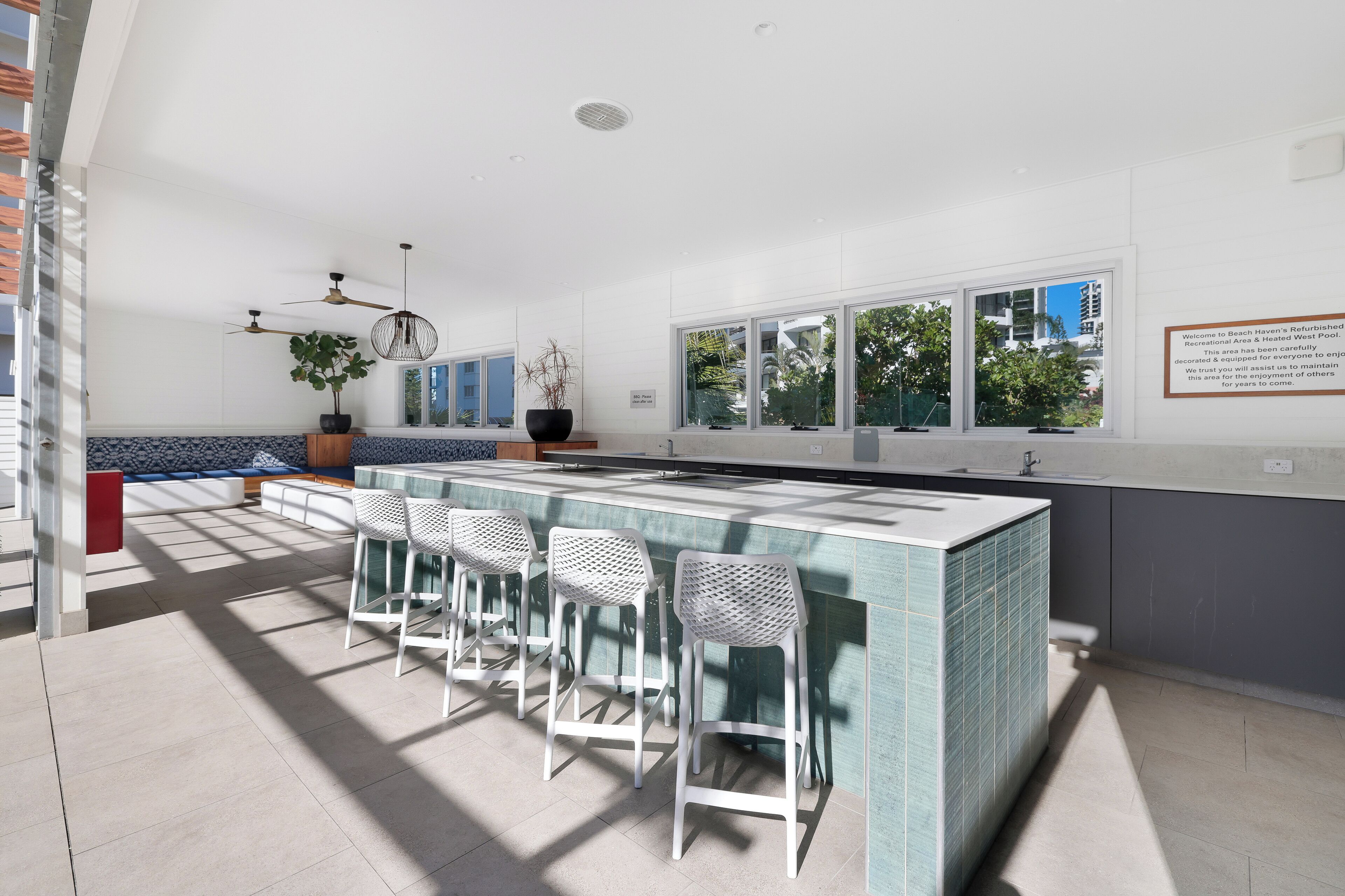 A modern kitchen with a large island, bar stools, and a view of the outdoors.