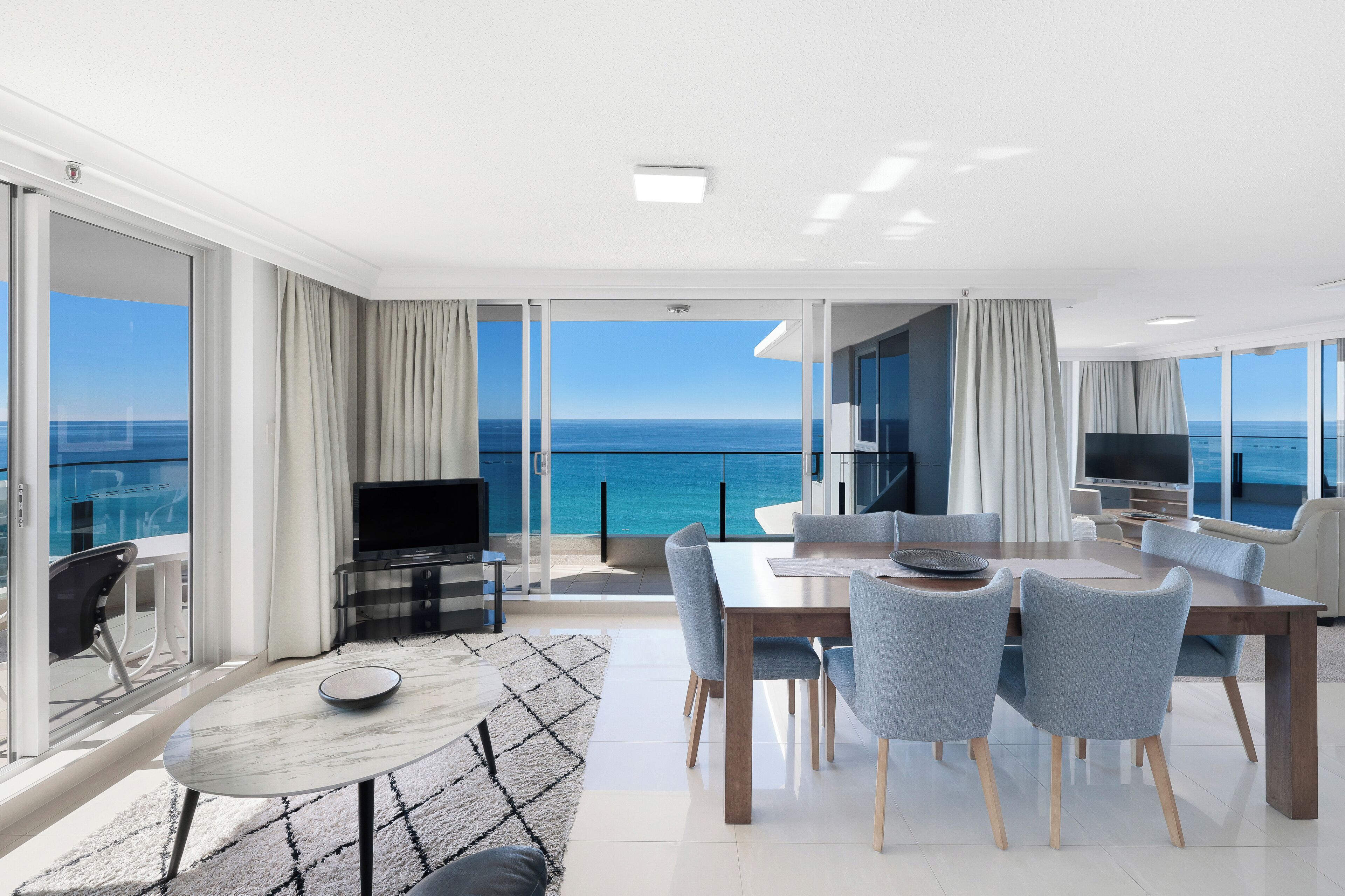 Un salón moderno con comedor, ventanas amplias y vistas al mar.