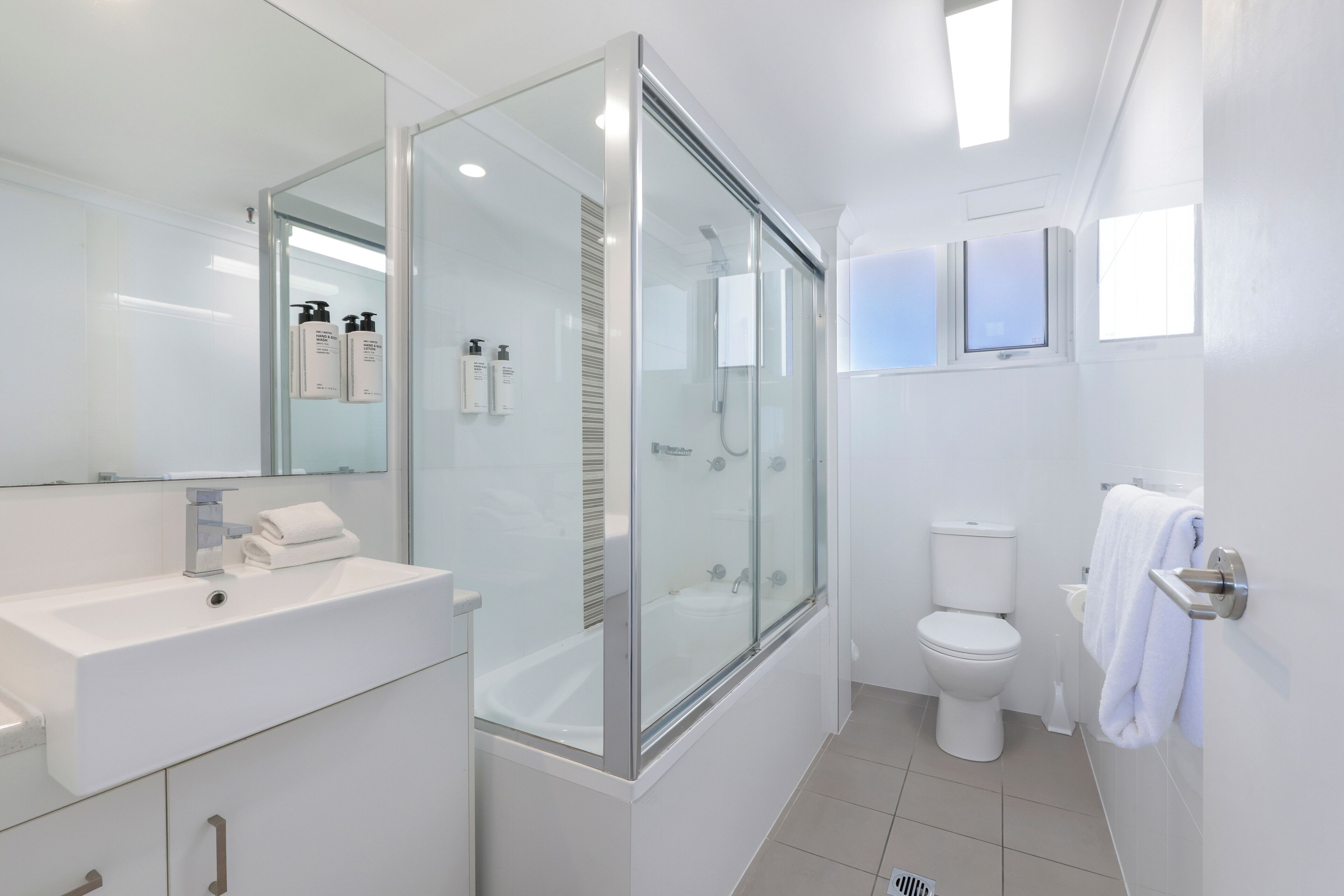 A modern bathroom with a glass-enclosed shower, a white sink, and a toilet.