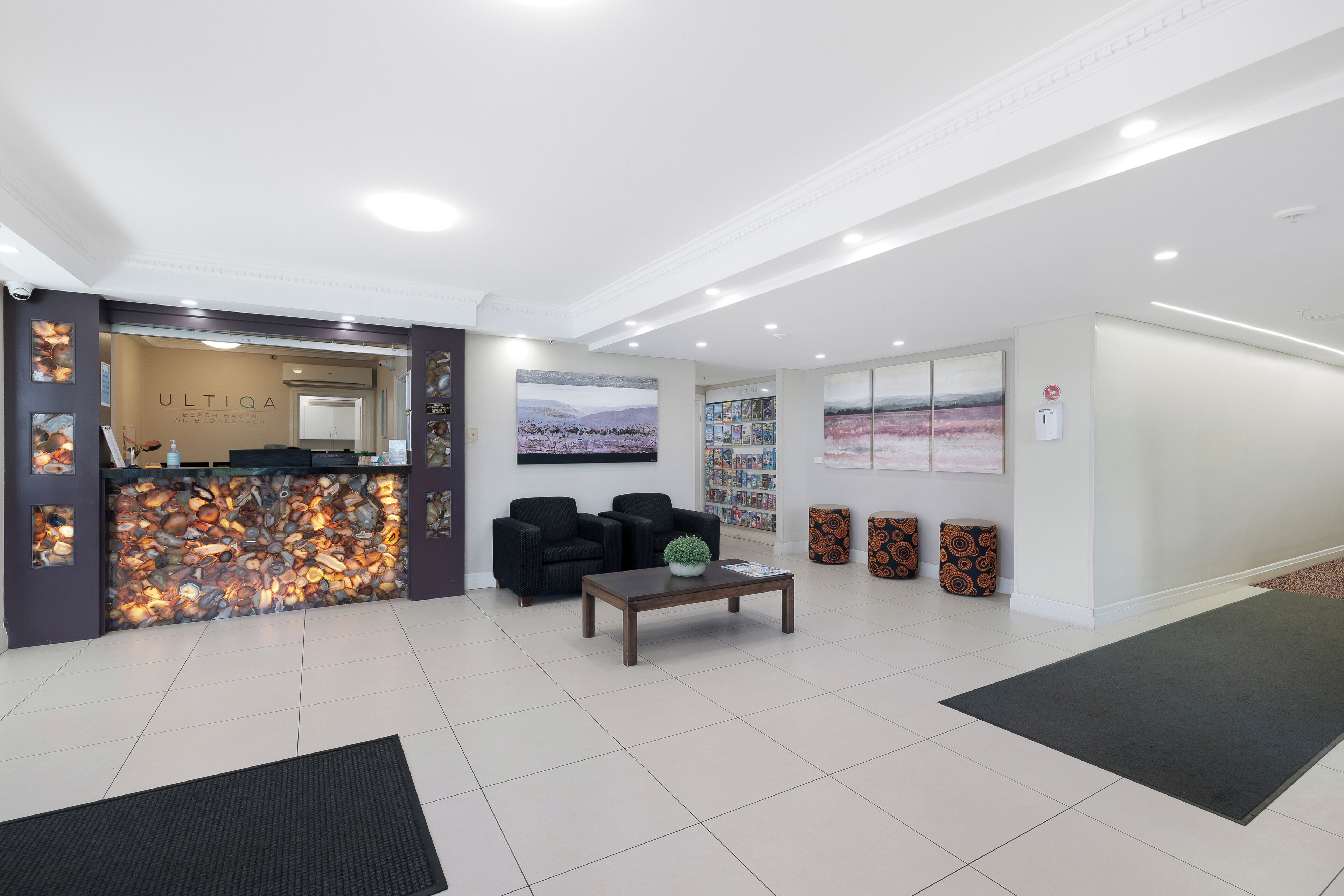 A modern lobby with a reception desk, seating area, and artwork on the walls.
