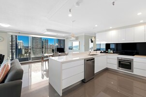 A modern kitchen with a central island, white cabinetry, and a dishwasher.