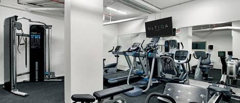 Un gimnasio moderno con diversos equipos de ejercicio, incluyendo cintas de correr, elípticas y estaciones de levantamiento de pesas.