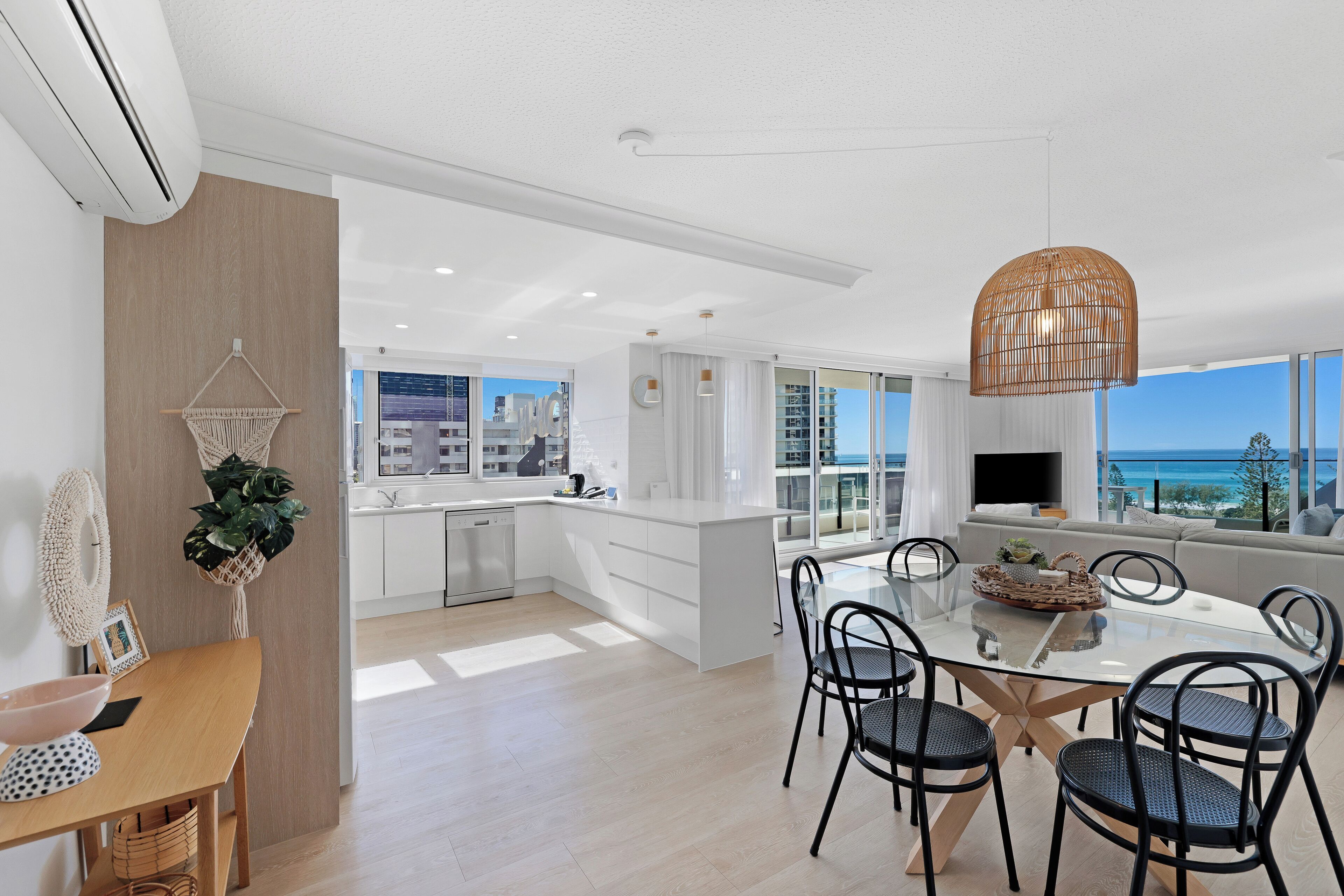 Una cocina moderna con comedor, ventanas amplias y vista al océano.