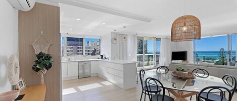 Una cocina moderna con comedor, ventanas amplias y vista al océano.