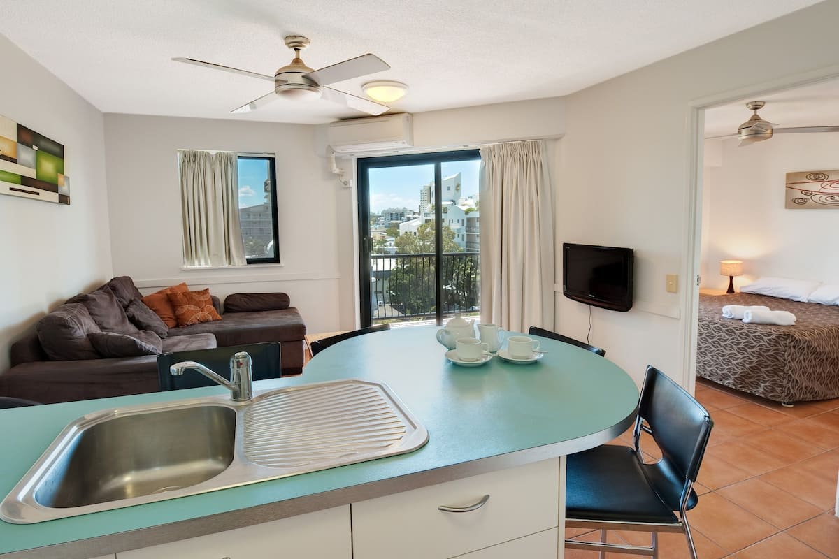 A compact living space with a kitchenette, a sofa, a dining area, and a bedroom.