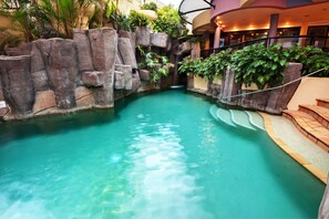 A pool with clear water, surrounded by rock formations and plants, and a curved balcony with a railing. - Nautilus Mooloolaba (Mooloolaba)