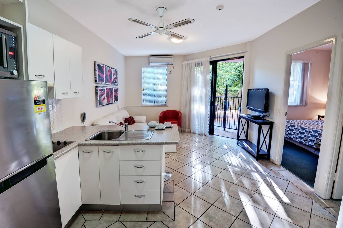 A modern kitchen with a built-in island, a refrigerator, and a ceiling fan.