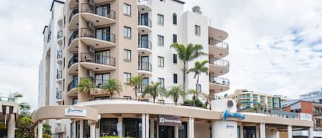 A multi-story hotel with balconies, a rooftop bar, and a parking area.