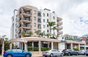 A multi-story hotel with balconies, a rooftop bar, and a parking area.