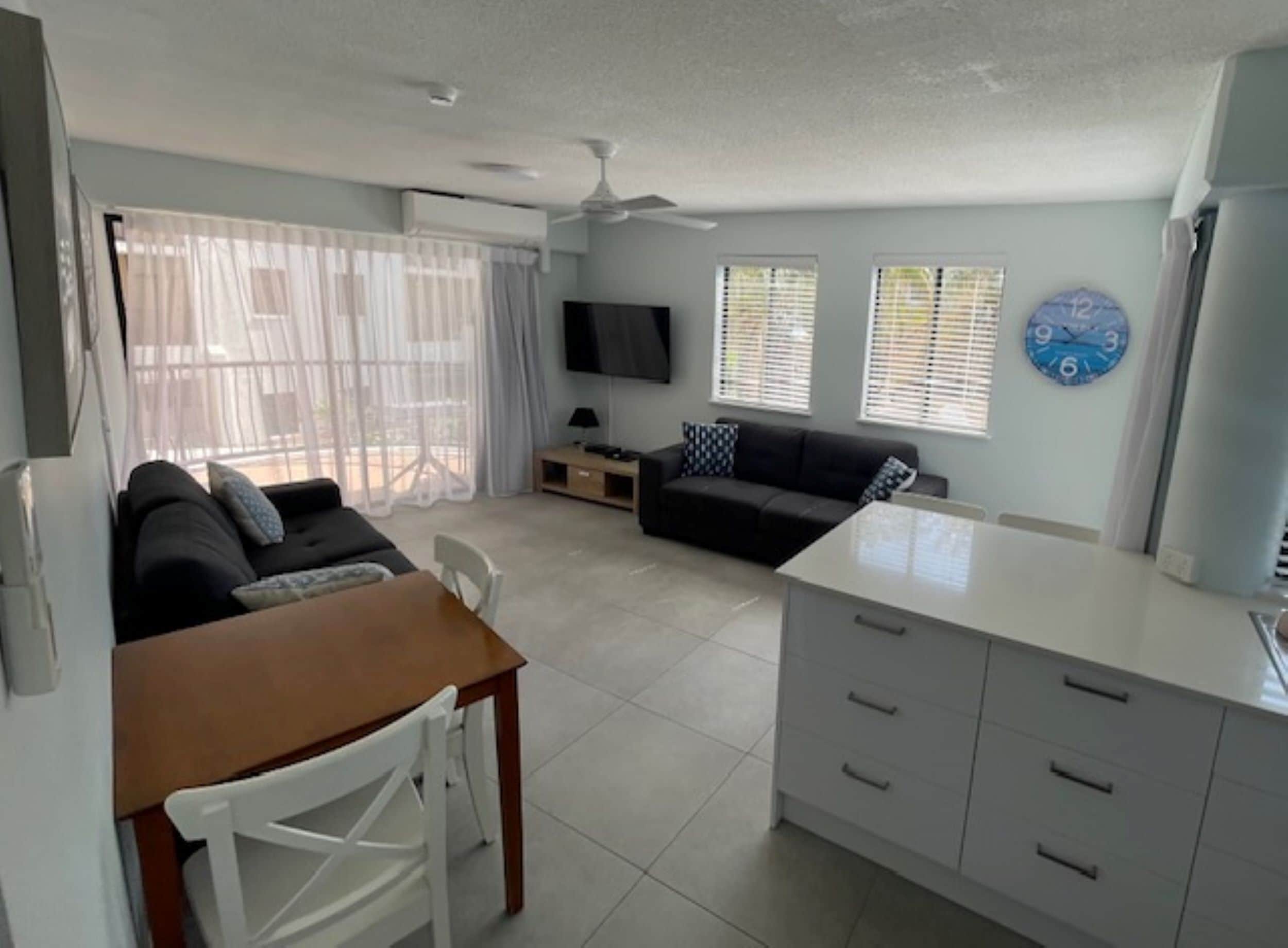A modern living room with a sofa, a dining table, and a TV.
