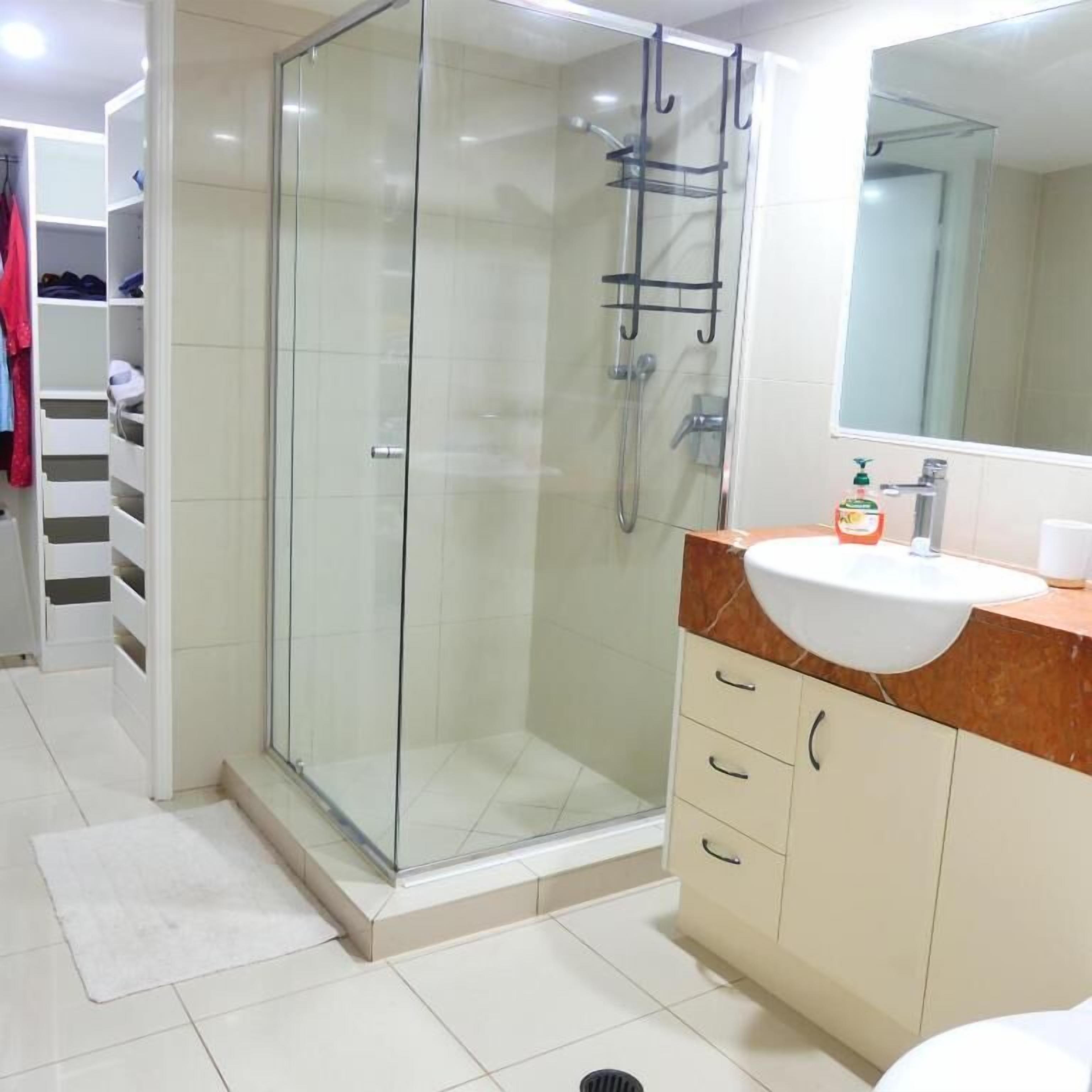 Une salle de bain moderne avec une douche à parois de verre, un meuble-lavabo et un miroir.