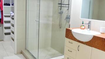 Une salle de bain moderne avec une douche à parois de verre, un meuble-lavabo et un miroir.