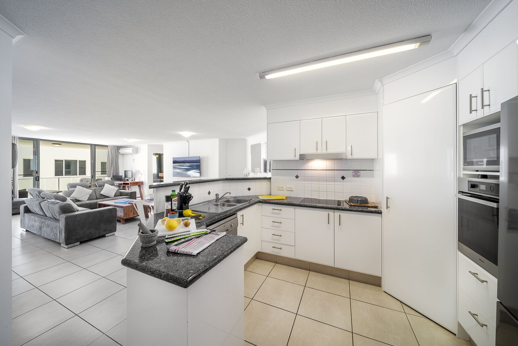 Una cocina moderna con armarios blancos, encimera de granito y electrodomésticos de acero inoxidable.