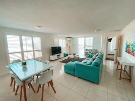 A modern living room with a sofa, TV, dining table, and chairs.