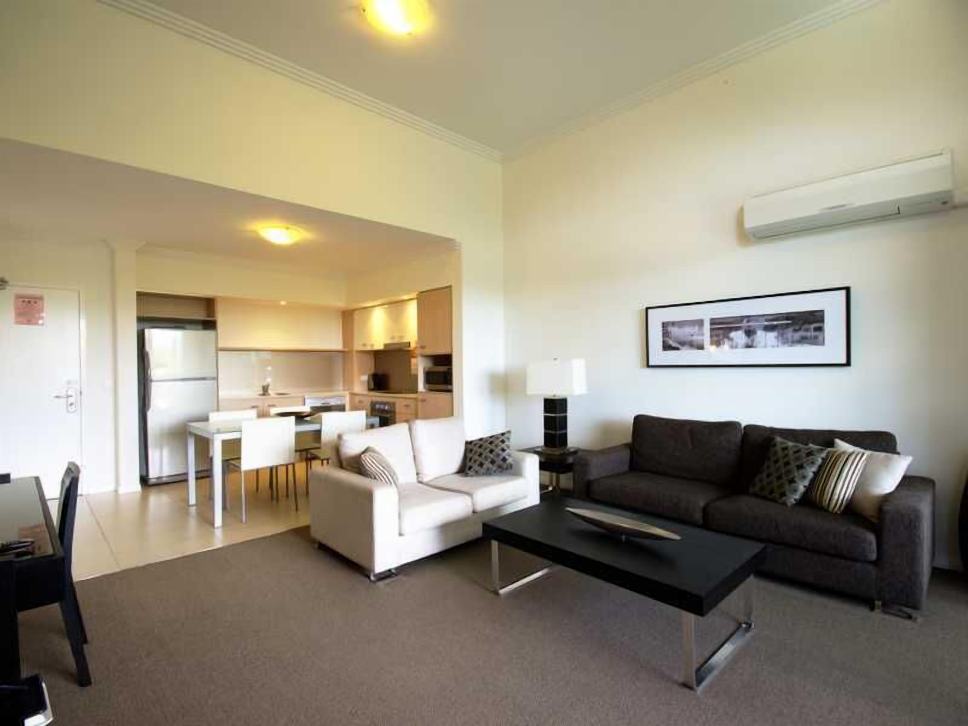 A modern living room with a sofa, a coffee table, and a dining area with a table and chairs.