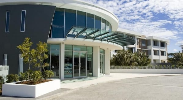 A modern building with a curved glass facade, a flat roof, and a white exterior.
