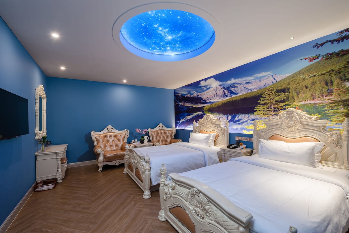 Une chambre avec deux lits, une table de chevet, une commode et une lucarne au plafond.