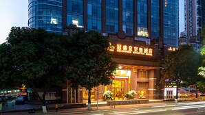 A modern hotel with a curved facade, large windows, and illuminated signage.