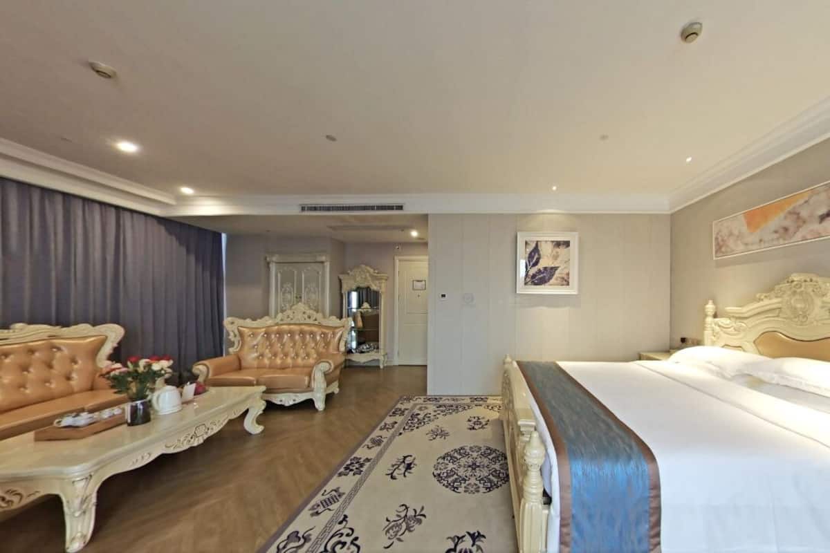 Une chambre d’hôtel avec un grand lit, un canapé, une table basse et un tapis décoratif.