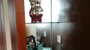 Ein Hotelzimmer mit einem grünen Tisch, einem Wasserkocher, einer Wasserflasche und einer dekorativen Vase mit roten Blumen.