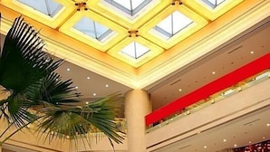 Ein mehrgeschossiges Atrium mit Glasdach, Palmen und roten Laternen.