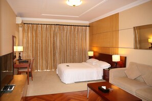 A hotel room with a bed, a sofa, a desk with a lamp, a chair, and a mirror. - The Star River Apartment (Guangzhou)