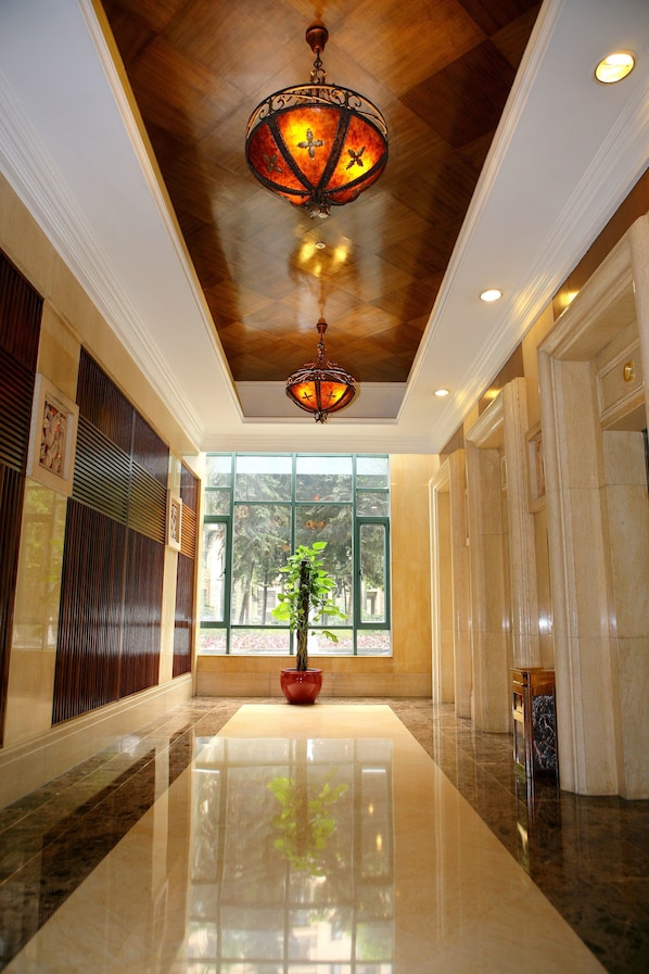 A polished lobby with a large window, a hanging lantern, and a potted plant.