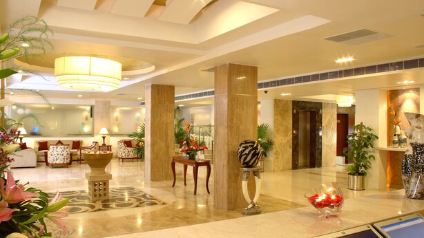 A spacious lobby with a reception desk, seating area, and a large chandelier.