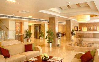 A spacious lobby with a reception desk, seating area, and a staircase.