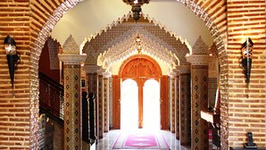 An arched hallway with patterned walls and a red carpet leading to a bright interior. - Palais Dar Ouladna (Marrakech)
