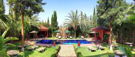 Una piscina al aire libre, sombrillas, tumbonas