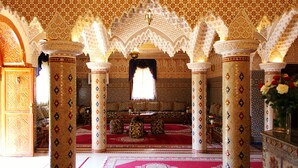 An ornate interior with intricate arches and columns, a central seating area with cushions, and a patterned floor. - Palais Dar Ouladna (Marrakech)