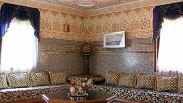 A room with a patterned ceiling, a sofa set, and a coffee table with a vase of flowers.