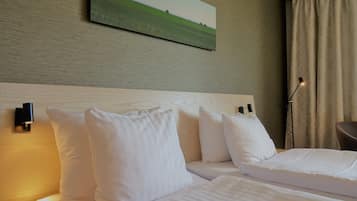 A hotel room with two beds, a headboard, a painting on the wall, a lamp, and a curtain.