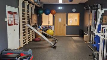 A gym with exercise equipment, a wooden rack, and a door with a poster.