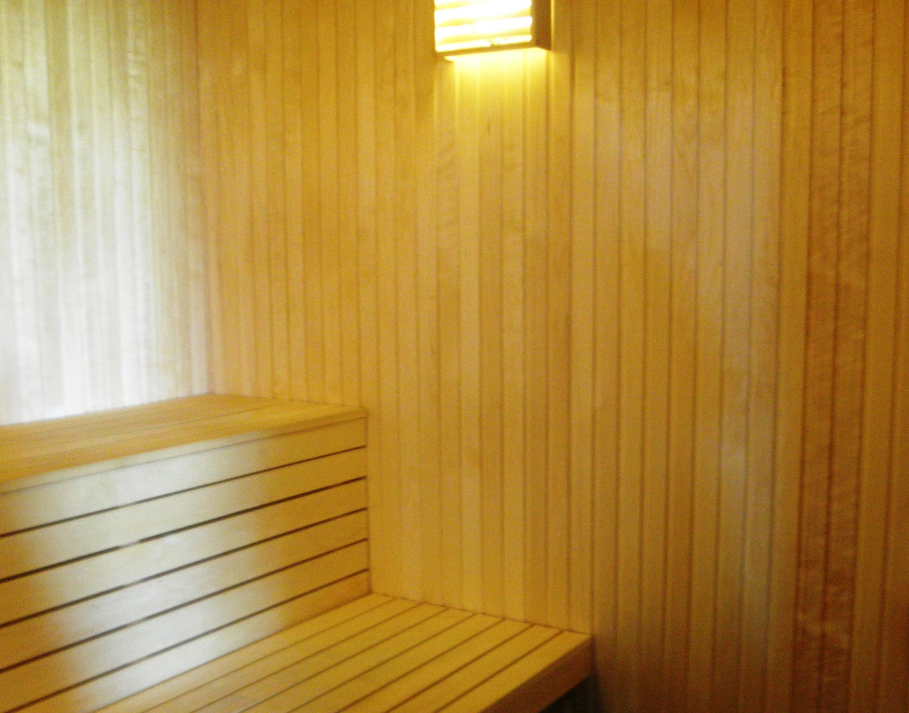 Un banco de madera en un sauna, con paneles verticales de madera.