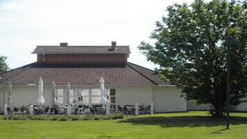 A building with a tiled roof and a covered outdoor seating area with tables and chairs.