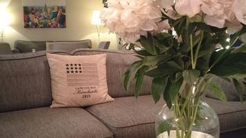 A living room with a grey sofa, a vase with flowers, and a decorative pillow.