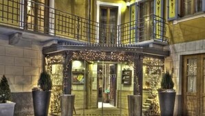 A hotel entrance with a glass door, a covered waiting area, and potted plants. - Le Miramonti Hotel & Wellness (La Thuile)