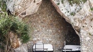 Una cueva de paredes de piedra con una silla blanca acolchada y una mesa.