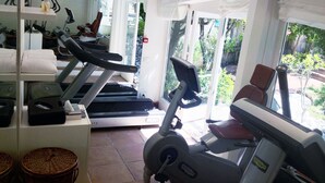 Un gimnasio con cintas de correr, bicicletas estáticas y un espejo grande.
