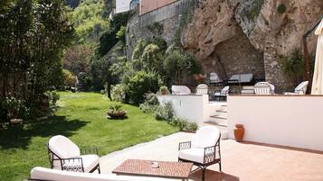 Une terrasse avec des meubles d’extérieur, un mur en pierre et un jardin.