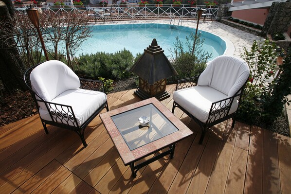 A poolside area with two white cushioned chairs, a glass-top table, and a decorative lantern. - La Locanda delle Donne Monache (Maratea)