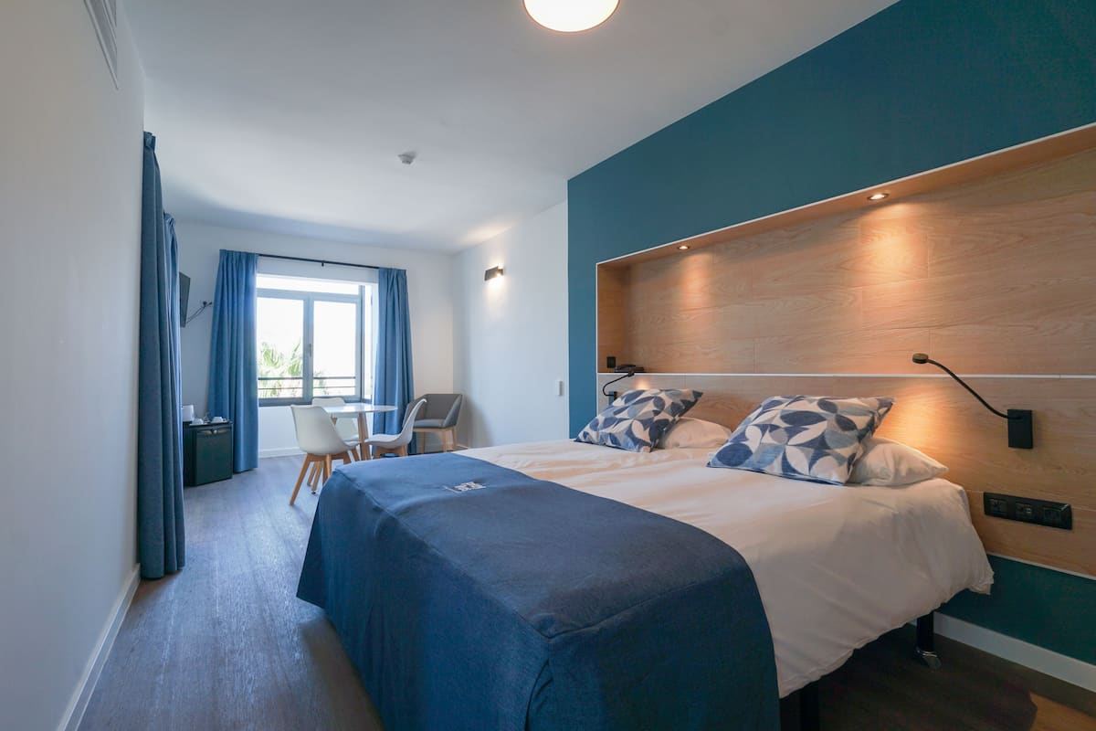 A modern hotel room with a large bed, a desk, and a chair.