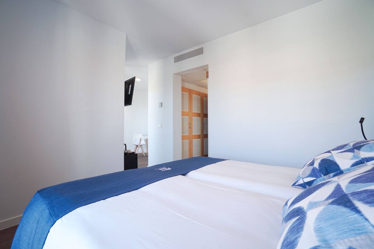 A bedroom with a bed, a blue blanket, and a wooden door in the background.