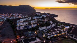 Un pueblo costero con edificios blancos, una playa y una montaña al fondo.