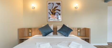 Une chambre d’hôtel avec un grand lit, deux tables de chevet, une œuvre d’art accrochée au mur et deux appliques murales.