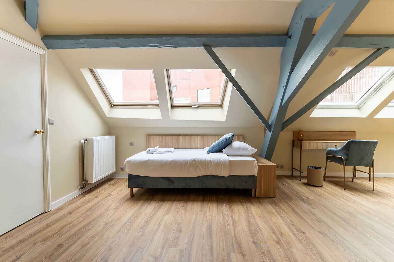 Un dormitorio con cama, escritorio y dos tragaluces.