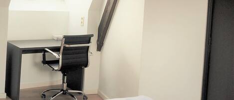 A hotel room with a desk, office chair, and neatly folded towels.