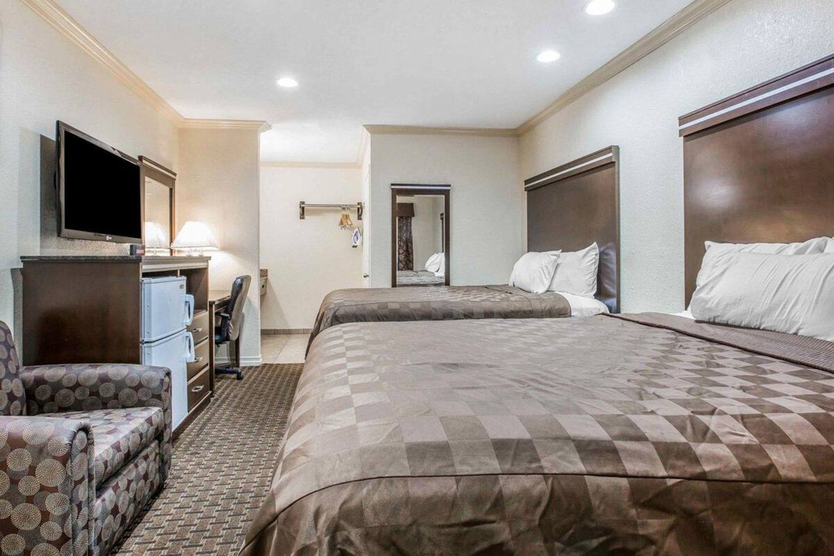 Una habitación de hotel con una cama grande, un escritorio con computadora, un televisor y una silla.